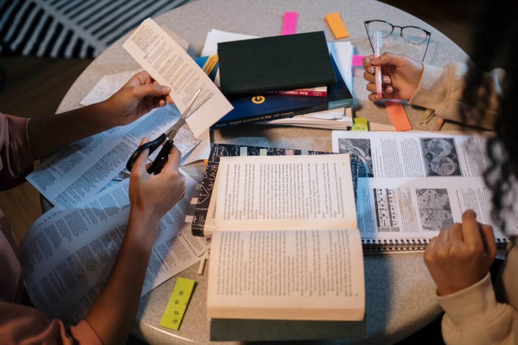 Two people preparing for a written assessment with books on table
