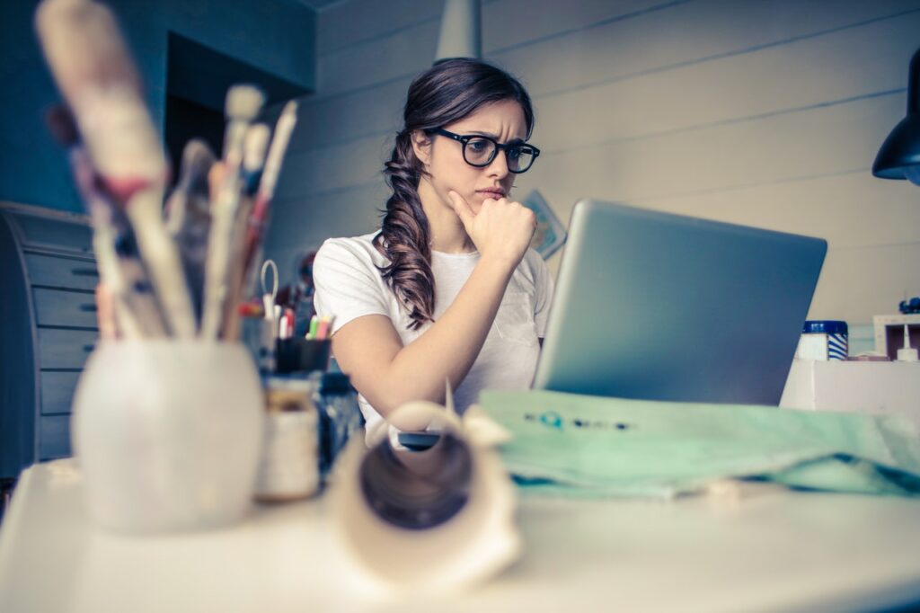 Young woman frowning or concentrating while working on her laptop
